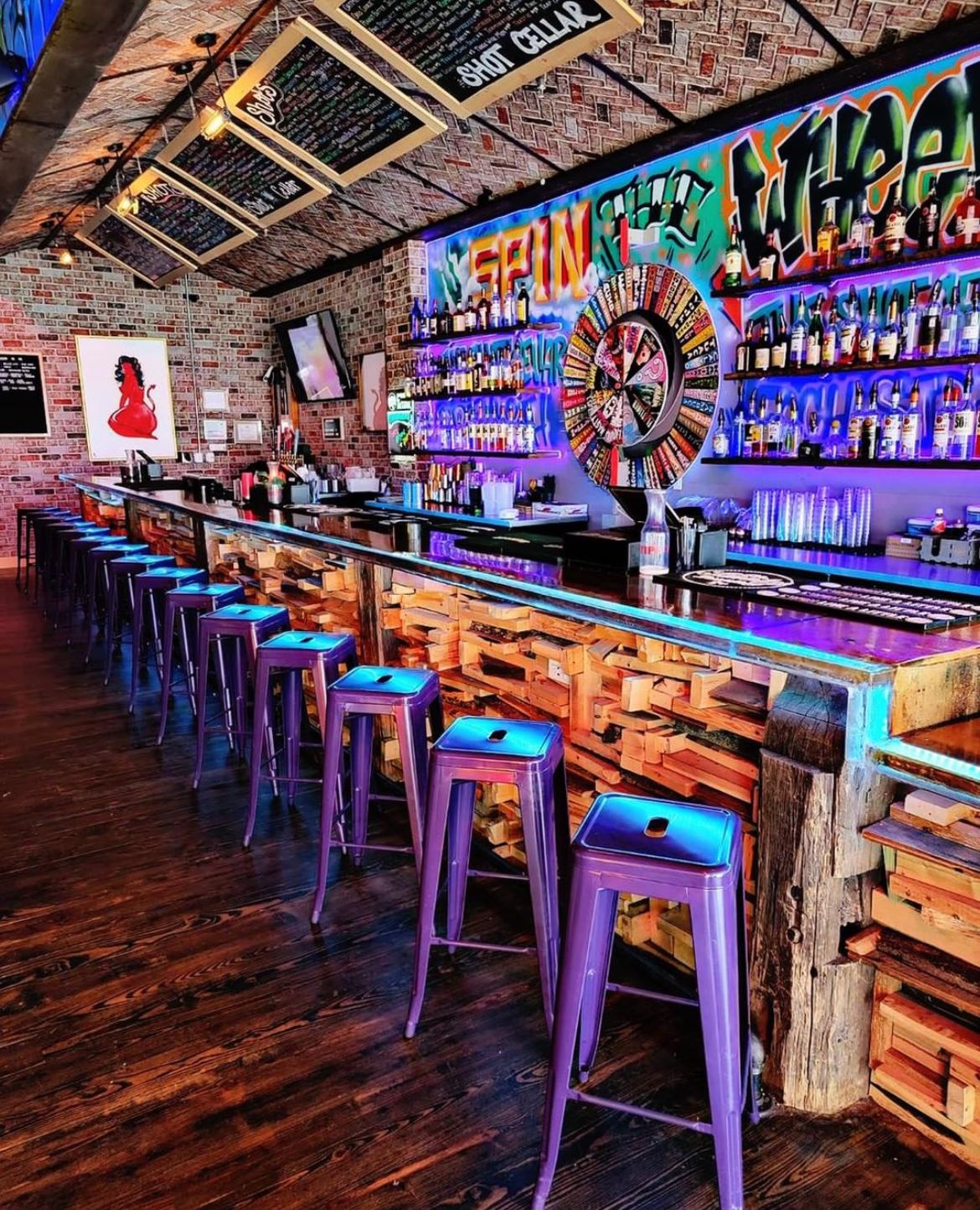 The Shot Cellar's main room: long bar, stools and neon