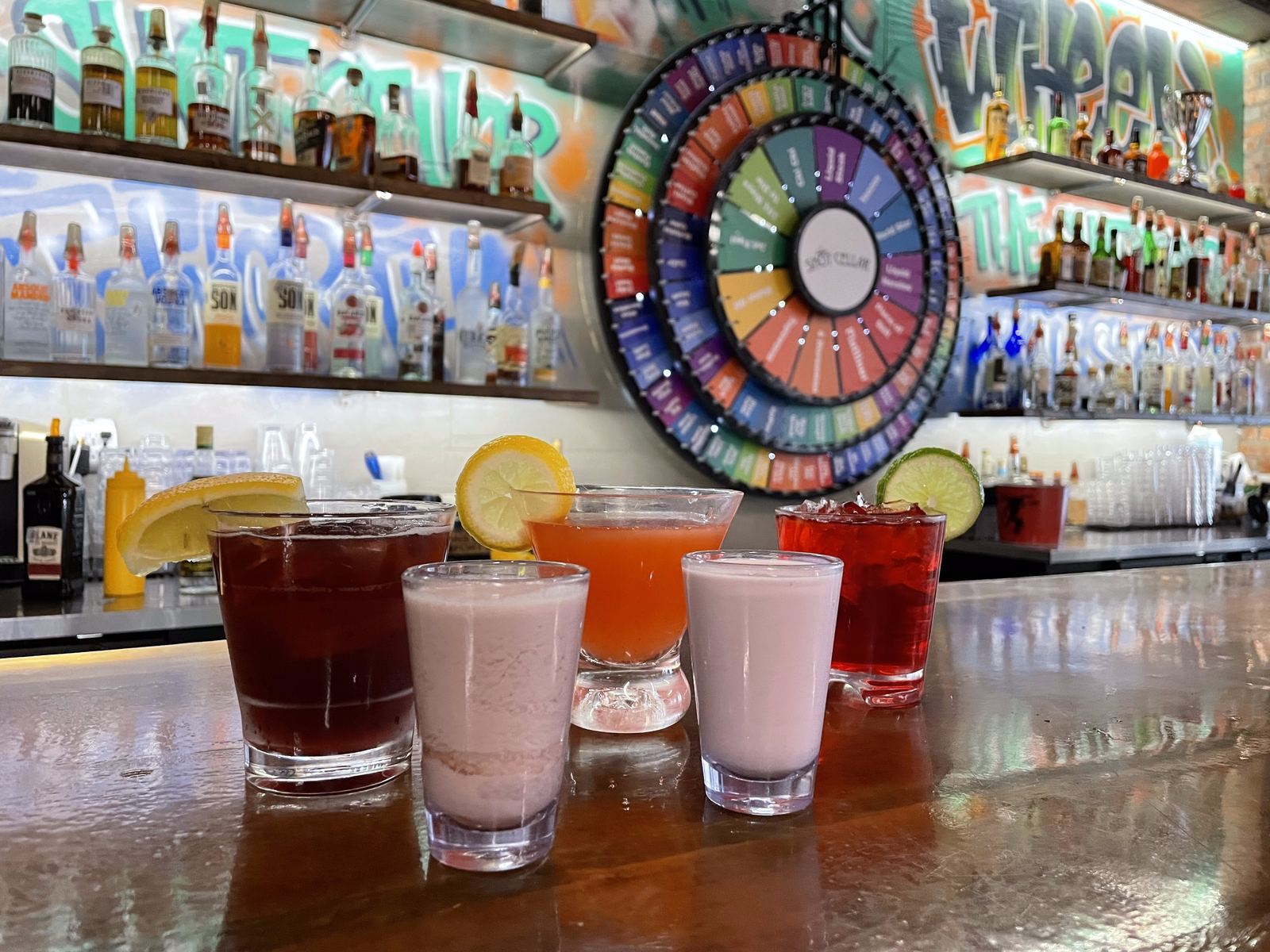 Five shots poured in a row along the bar with the wheel behind them